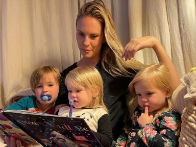 Cassidy Boesch is reading the children's book with Logan, Annabelle, and Evie Page.